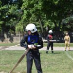 DSC_0377 Na obrazach, które otrzymali podczas szkoleń, ubranych w stroje i kaski. Trzymają węże strażackie, ćwicząc na tle drewna i drewnianego ogrodzenia.