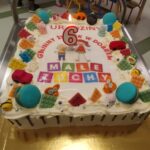 Na obrazku znajdują się torty urodzinowe ozdobione dekoracjami oraz świeczką w liczbie 6. Na torcie widać napisy „Małe Tuchy”.