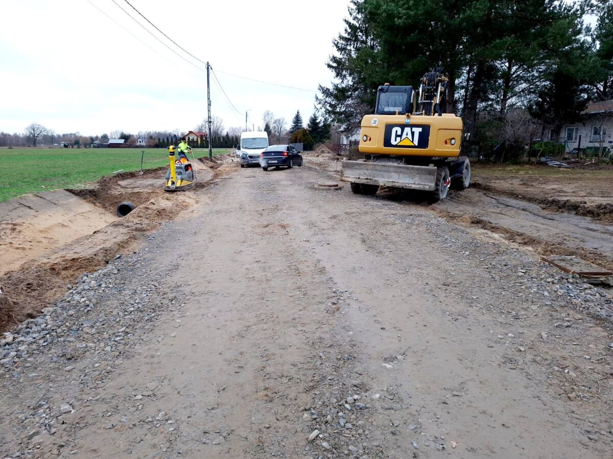 Na widocznym miejscu, w trakcie budowy, po prawej stronie, której stoina jest koparka. Obok dróg znajdują się dwa dodatkowe, a przy nich widoczni są pracownicy wykonujący jakiekolwiek zadania.