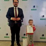 484978407_675892694786255_2428853877217418122_n Na miejscu znajduje się dorosły i dziecko w pomieszczeniu; trzyma dyplom i prezenty na prezentach. W tle widoczny jest napis „Gmina Dobre”, co charakterystyczne, że scena ma miejsce podczas poszczególnych wydarzeń lub ceremonii wręczenia nagród.