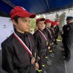 501179822_728983746143816_4168556237040726443_n Młodzi strażacy w czarnych mundurach i czerwonych czapkach stoją na podium. Mają medale na szyjach. W tle widać ścianę z logo Gminy Dobre.