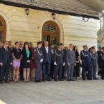 518448075_763804992661691_683559030176822102_n Grupa ludzi ubrana formalnie stoi przed jasnym budynkiem z łukowatymi oknami. W tle widać kremową ścianę i drewniane ramy okien. Niektórzy noszą mundury, inni garnitury i sukienki.