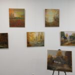 Ściana z sześcioma obrazami o tematyce jesiennej. Dominują brązy, czerwienie i złoto. Tło to biała ściana galerii.