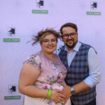 Dwoje uśmiechniętych osób, kobieta w różowej sukni z wiankiem i mężczyzna w kamizelce. Tło z logo Gmina Dobre. Zieleń po lewej.