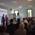 5 Dwoje ludzi przemawia na scenie przy białym ekranie z napisem Mazowsze. Obok stoją dwa banery. Publiczność siedzi w jasnym pomieszczeniu.