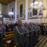 DSC_5366 Wnętrze kościoła z żołnierzami w szarych mundurach na pierwszym planie. Tło ozdobione malowidłami i wiszącymi żyrandolami. W ławkach siedzą ludzie, drewniana podłoga z biało-czarnymi