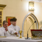 DSC_7758 Wnętrze kościoła, kilku ministrantów w białych szatach przy ołtarzu. Złote i kremowe tło, jasne światło. Kapłan w złotej szacie, widać kielich.