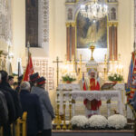 DSC_7781 Na zdjęciu widoczna jest msza w kościele, z księdzem przy ołtarzu. W tle są jasne ściany i obrazy, wokół zgromadzeni wierni. Dekoracje w kolorach bieli i złota dominują scenę.