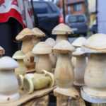 Drewniane grzyby na jucie, w tle auto i domy; tło niebieskie. Kolory naturalne, dominują beże. Wystrój ozdobiony czerwonymi sercami.