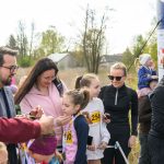 DSC_5516 Grupa ludzi na zewnątrz odbiera medale. W tle drzewa i niebo. Ubrani w kolorowe stroje sportowe.