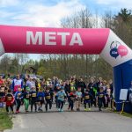 DSC_5530 Start dziecięcego biegu pod różowo-niebieskim łukiem z napisem META. Tło to drzewa i niebo. Liczny tłum kibiców.