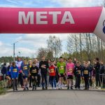DSC_5614 Grupa dzieci stoi na starcie wyścigu pod różowo-białym balonem z napisem META. W tle drzewa i niebo. Po lewej stoper pokazuje 0:00:00.