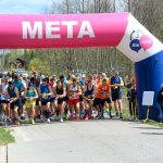 DSC_6001 Grupa biegaczy startuje spod różowo-białego balonu z napisem META. Tło stanowią drzewa i niebo. Uczestnicy są ubrani kolorowo.