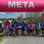 DSC_6060 Zawodnicy stoją pod różowo-białą bramką z napisem META. Są ubrani w kolorowe stroje sportowe. W tle widać drzewa i niebo z chmurami.