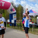DSC_6188 Biegacze przy mecie pod różowym łukiem, z czasem 28:55. Jeden z nich ubrany w biało-niebieski strój, drugi w czarno-biały, obok namiot.